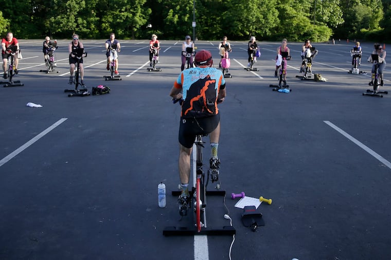 Cycling instructor Tom Hambrose (foreground) leads the 45 minute “Cycling with Tom” spin class in the parking lot at Royal Fitness in Barrington, N.J. on May 27, 2020.
