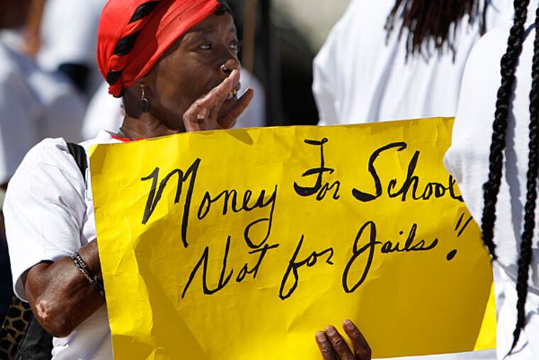 Hazel McGirt, a school district employee, holds up a sign during a protest in front of the School District of Philadelphia headquarters in Philadelphia on August 14, 2013. A group of parents, students, and clergy lined the steps in front of the school district headquarters for a one-day resumption of fasting to bring attention to the 1,202 laid-off student safety staff. ( DAVID MAIALETTI / Staff Photographer )