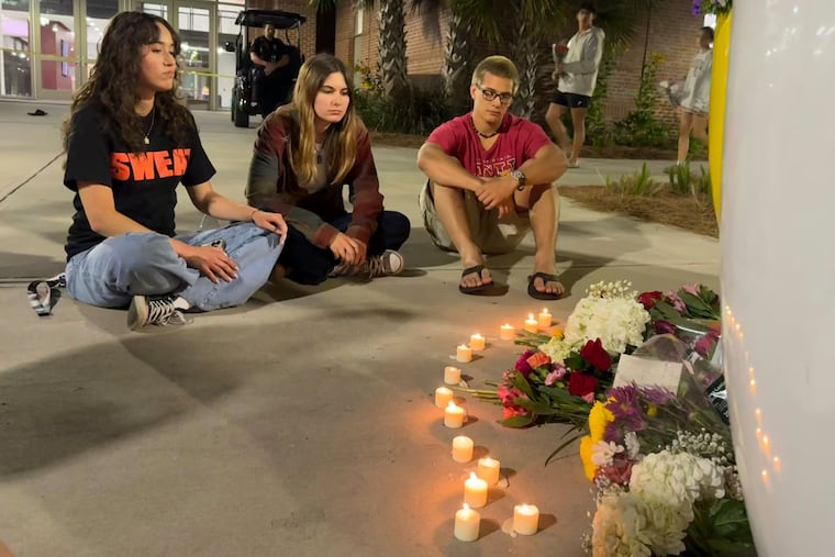 People sit in front of a makeshift memorial outside the student union at Florida State following a campus shooting on Thursday.