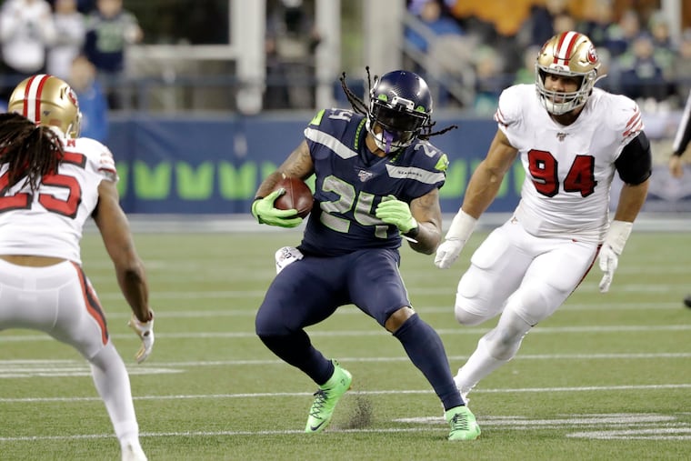 Marshawn Lynch (24) runs between San Francisco's Richard Sherman (left) and Solomon Thomas on Sunday.