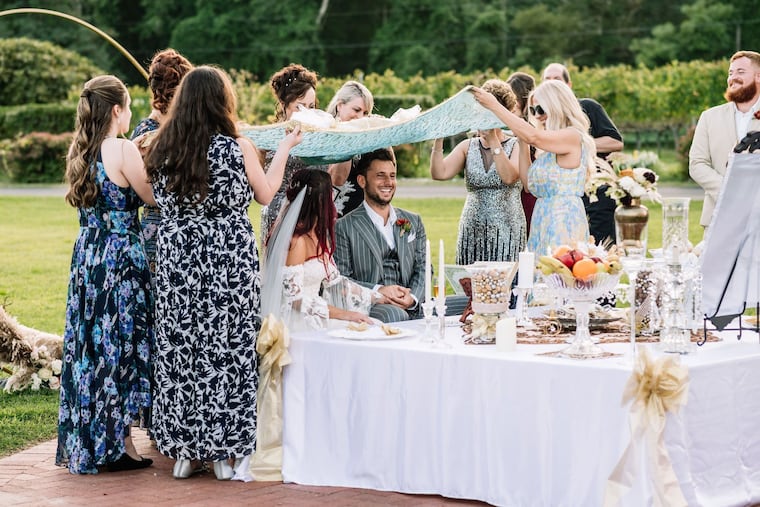 AnnaLisa's and Amir's mothers, alongside cousins and aunts, hold a cloth over their heads during the ceremony.