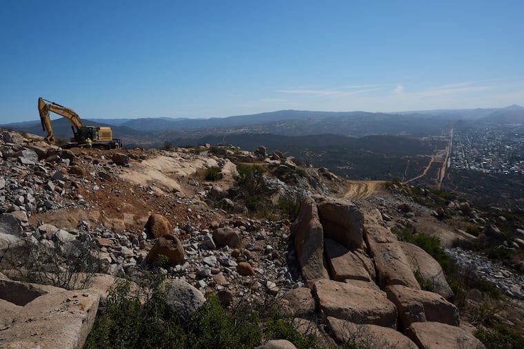 Construction crews work on a new border wall segment on Kuuchamaa Mountain, Friday, April 24, 2026, seen from Tecate, Mexico.