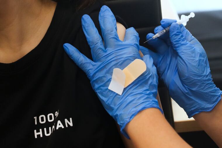 A COVID-19 vaccine is administered by pharmacist Allen Lee of SunRay Drugs at the Crane Community Center in Philadelphia in July.