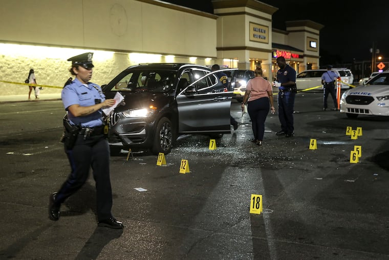 Police officers from the 35th District process the scene outside the ShopRite on East Olney Avenue where a man, 18, was fatally shot and a woman, 19 was injured while sitting inside a BMW SUV in the parking lot on Monday, Aug.16, 2021.