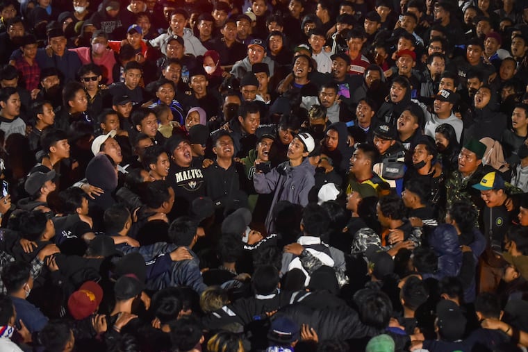 Soccer fans chant slogans during a vigil for the victims of Saturday's soccer riots in Malang, East Java, Indonesia, on Sunday.