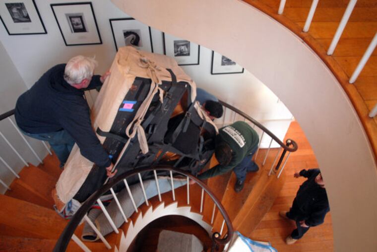Movers carry a 7-foot Steinway Model B grand piano down the spiral staircase at a Jenkintown site.