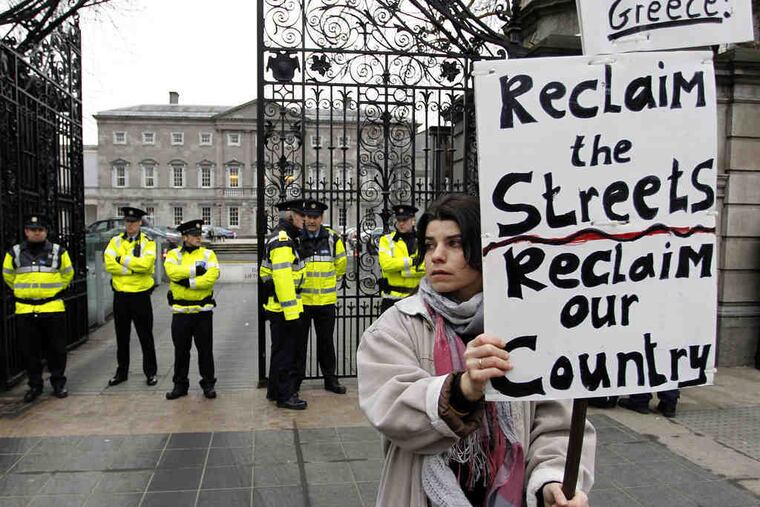 A protester carries a sign outside Leinster House in Dublin. Lawmakers voted on Wednesday to back a 67.5 billion-euro international rescue despite high interest rates from EU partners.