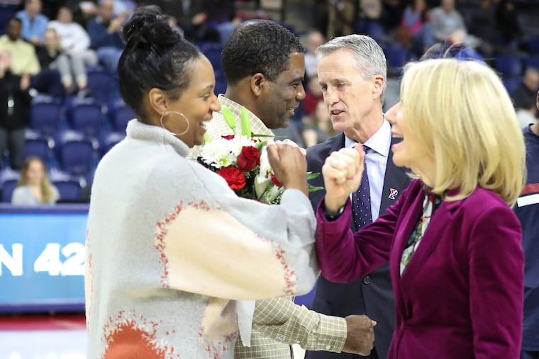 Penn Basketball head coach Steve Donahue (center) and Penn President Amy Gutmann (right) give parents of senior basketball players fist and elbow bumps rather than handshakes due to COVID-19 precautions before a men's basketball game at the Palestra on Saturday.