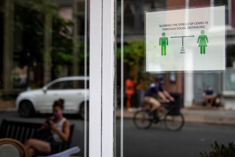 A sign reminds people to social distance by standing six feet apart on the window of Twenty Manning Grill 20th Street.