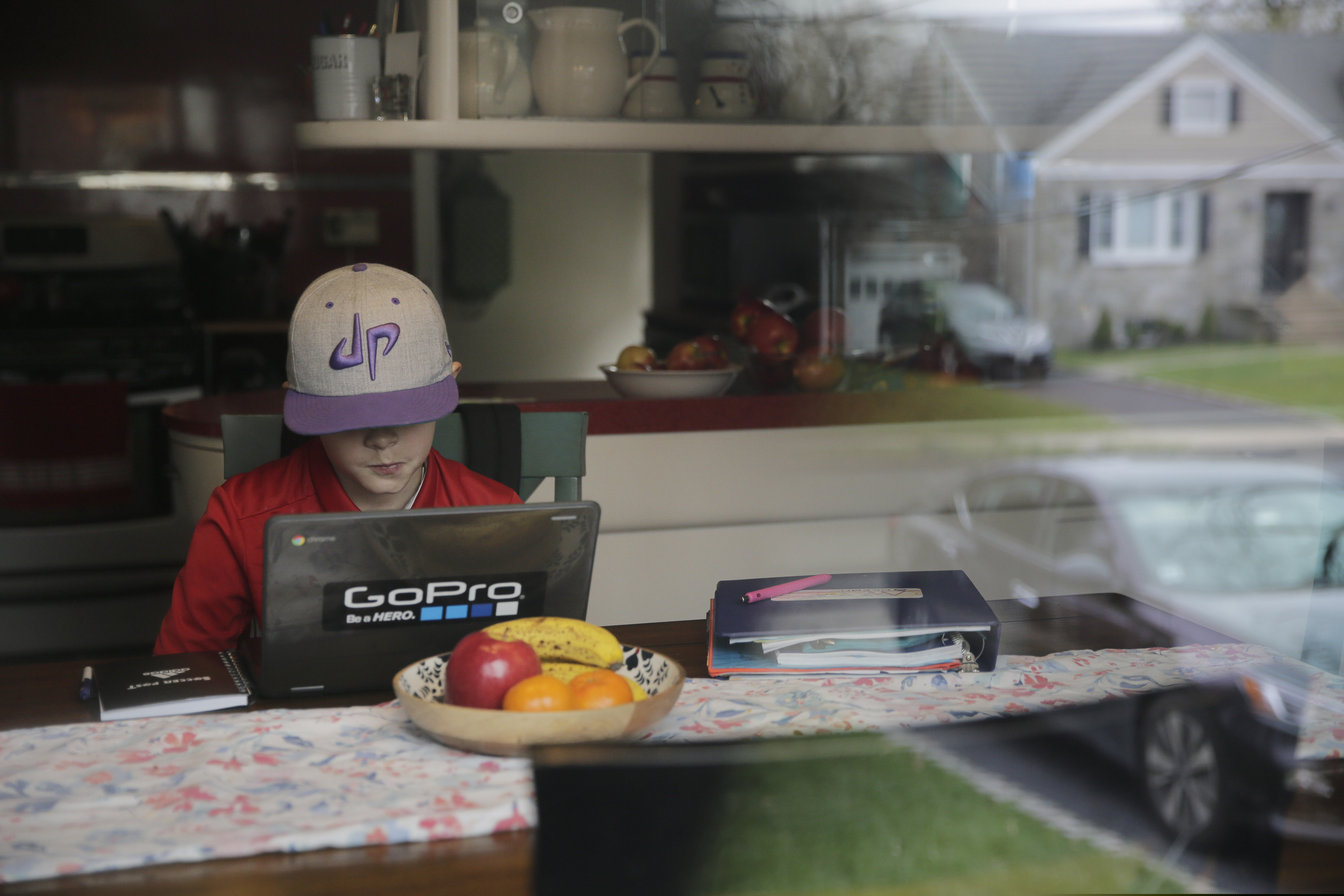 The outside is reflected in a window as Colin Powers, 9, streams a math lesson broadcast by public television on a laptop at his home in Union, N.J. Colin's teachers are supplementing their own lesson plans with a new live broadcast called NJTV Learning Live where teachers broadcast live lesson to specific grades at different times of the day.