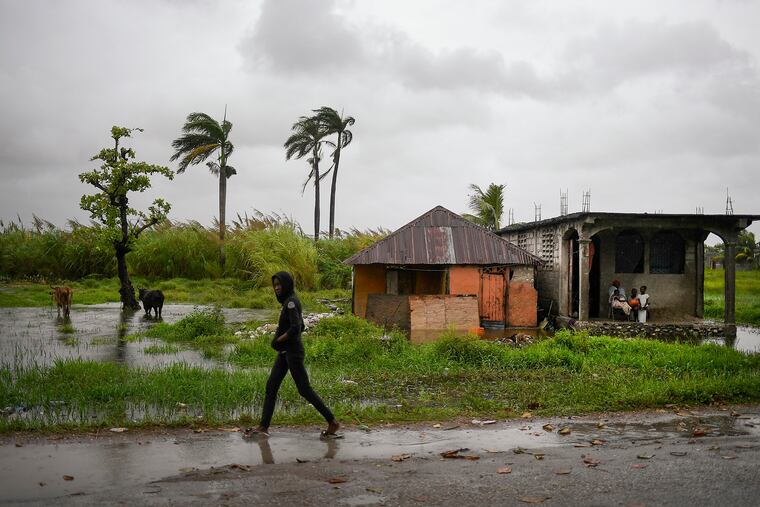 A man walks along a road in a slightly flooded area the morning after Tropical Storm Grace swept over the area in Trou Mahot, Haiti.