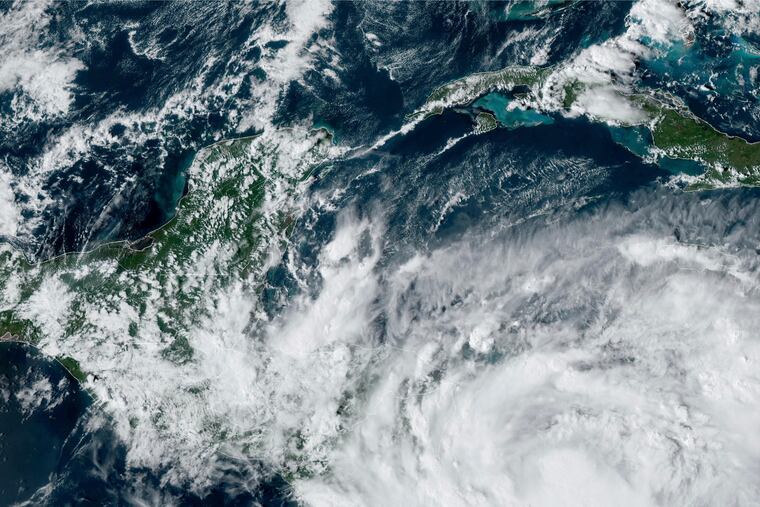 This Saturday, Oct. 8, 2022 satellite image made available by the U.S. National Oceanic and Atmospheric Administration shows Tropical Storm Julia, bottom right, at 4 p.m. EDT.