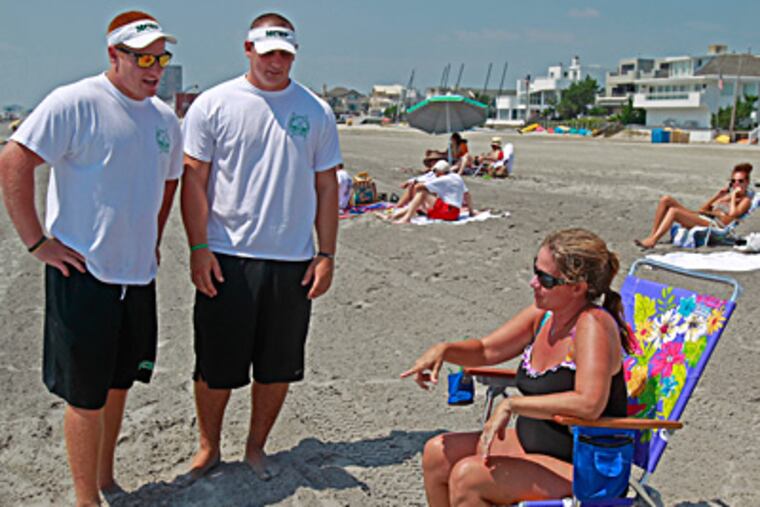 Beach badge bouncers Tim Goodwin (left) and Andrew Baumgardner talk with Linda O'Neill of Claymont, Del. The two men, both college football players, help Margate's beach-badge checkers enforce the town's tag law. (Akira Suwa/Staff)