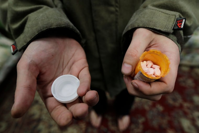 In this Nov. 14, 2019 photo, Jon Combes holds his bottle of buprenorphine, a medicine that prevents withdrawal sickness in people trying to stop using opiates, as he prepares to take a dose in a clinic in Olympia, Wash.