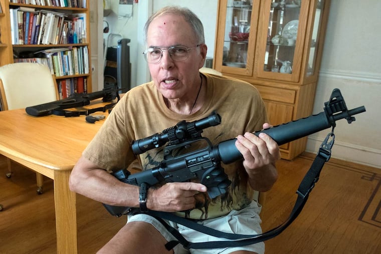 Tom Nelson, local Pink Pistols chapter president, at his dining room table holding his Colt AR-15 rifle.