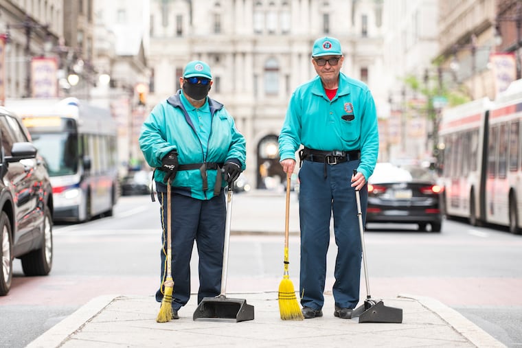 Ed Vinlaun (left) and Tom Fitzmaurice (right) pose for a portrait in the middle of Broad Street on Wednesday, April 29, 2026. Both Vinlaun and Fitzmaurice have worked as street sweepers for the Center City District for 35 years.