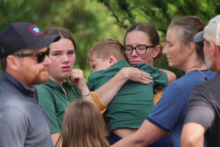 Parents comfort their children after a shooting at Annunciation Church on Wednesday in Minneapolis.