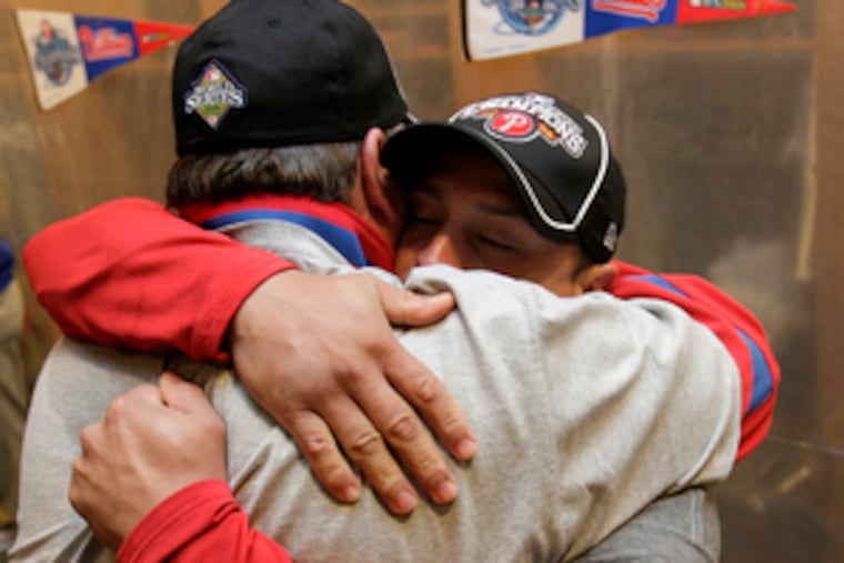 Pitching coach Rich Dubee (left) embraces catcher Carlos Ruiz in the clubhouse after the win.