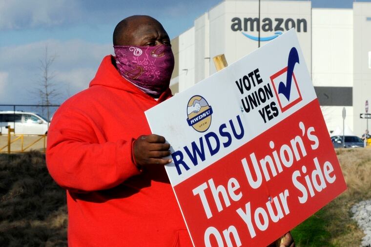 Michael Foster of the Retail, Wholesale and Department Store Union holds a sign outside an Amazon facility where labor is trying to organize workers in Bessemer, Ala., on Feb. 9, 2021. On Tuesday, Jan. 11, 2022, the National Labor Relations Board said that Amazon workers in the Bessemer facility will vote by mail in February 2022 in a re-run election to decide whether or not to unionize.