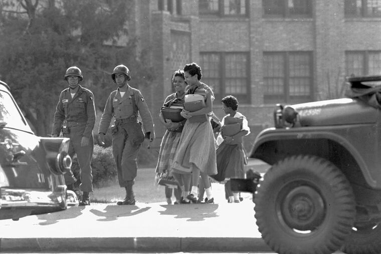 Two paratroop officers escort black students from Central High School in Little Rock, Ark., September 27, 1957. School was closing for the weekend.