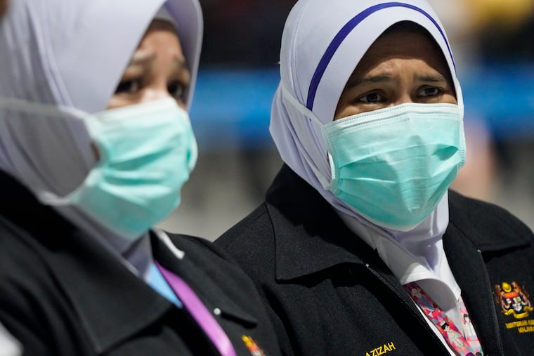 Health officials wear face masks at an inspection site at the Kuala Lumpur International Airport in Sepang, Malaysia, Tuesday, Jan. 21, 2020. Countries both in the Asia-Pacific and elsewhere have initiated body temperature checks at airports, railway stations, and along highways in hopes of catching those at risk of carrying a new coronavirus that has sickened more than 200 people in China.