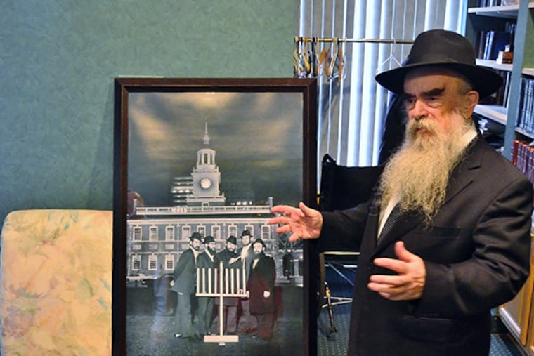 Rabbi Abraham Shemtov, head of the local Lubavitcher sect of hasidic Judaism, talks about a picture of the first official menorah on Independence Mall. (C.F. Sanchez / Staff Photographer)