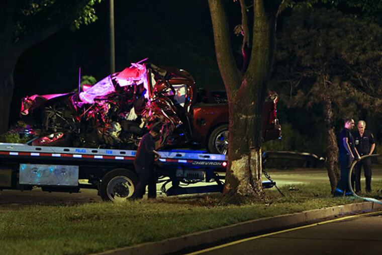 JOSEPH KACZMAREK / FOR THE DAILY NEWS A police tow truck removes a heavily damaged Dodge pickup truck yesterday from Henry Avenue in Roxborough, the scene of a crash that killed an off-duty Philly police officer.