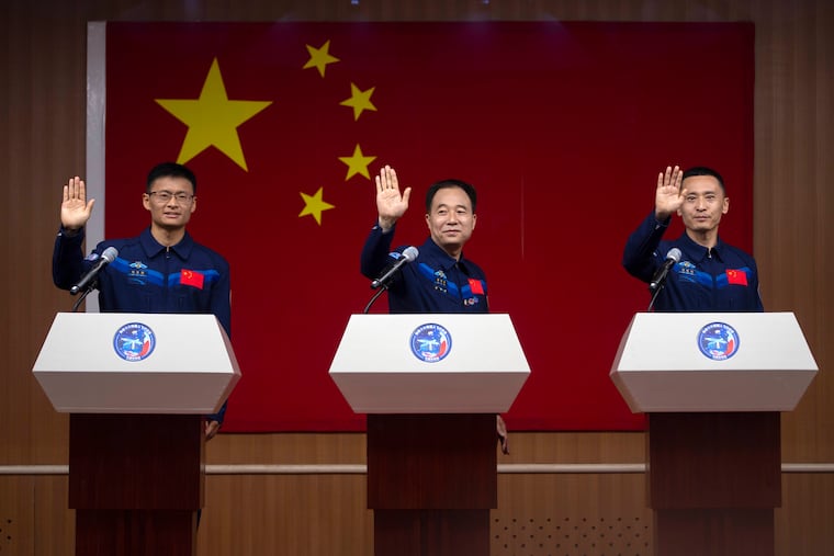 Chinese astronauts for the upcoming Shenzhou-16 mission, from left, Gui Haichao, Jing Haipeng, and Zhu Yangzhu wave as they stand behind glass during a meeting with the press at the Jiuquan Satellite Launch Center in northwest China on Monday.