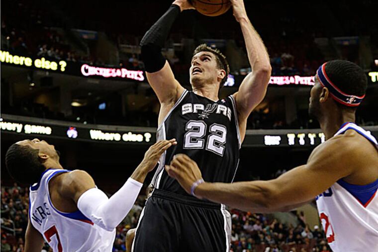 The Spurs' Tiago Splitter goes up for a shot as the 76ers' Darius Morris and Brandon Davies defend during the first half. (Matt Slocum/AP)