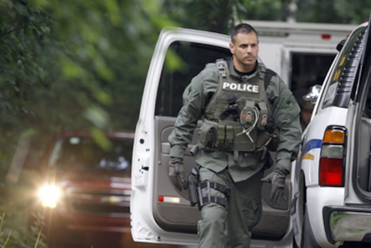 A police officer walks by vehicles on Renninger Road in Douglass Township, as he arrives Sunday near the scene of a fatal shooting. <a href="http://www.philly.com/philly/gallery/20110704_Gunman_sought_after_2_killed__3_wounded_in_Douglass_Township.html"><b>Click here to see photo gallery.</b></a>
(Jacqueline Larma / AP Photo)