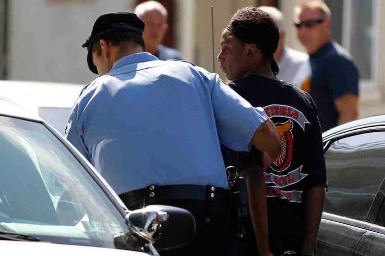 A cop leads away a handcuffed Wheels of Soul member.