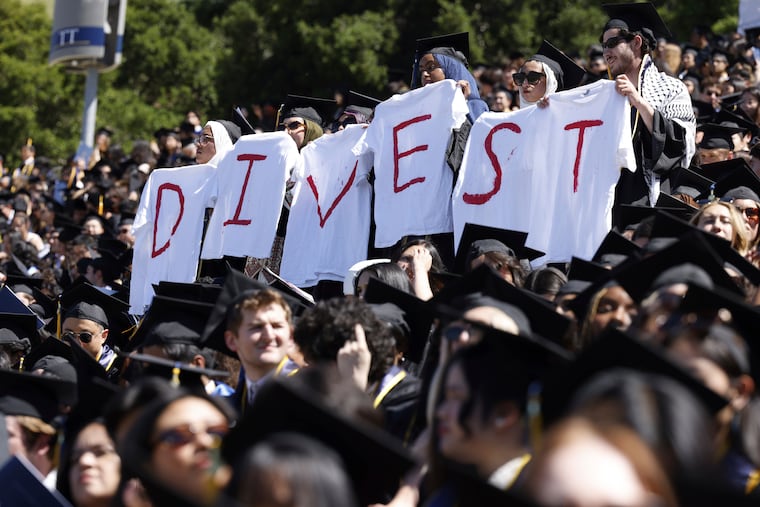 Pro-Palestinian students hold white t-shirts stating the message "DIVEST" as they protest during the UC Berkeley graduation on Saturday, May 11, 2024.
