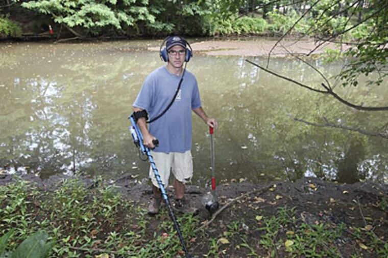 Neil Schwartz with his metal-detecting equipment searches for so-called Henning nickels July 4 on the banks of the Cooper River in Pennypacker Park in Haddonfield. (Steven M. Falk/Staff)