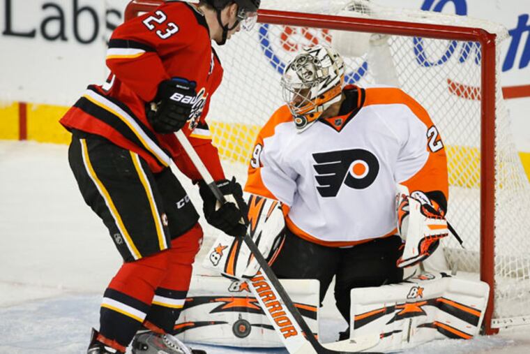 Ray Emery (right) stops a shot from Calgary Flames' Sean Monahan during the second period of an NHL hockey game in Calgary, Alberta, Tuesday, Dec. 31, 2013. (AP Photo/The Canadian Press, Jeff McIntosh)