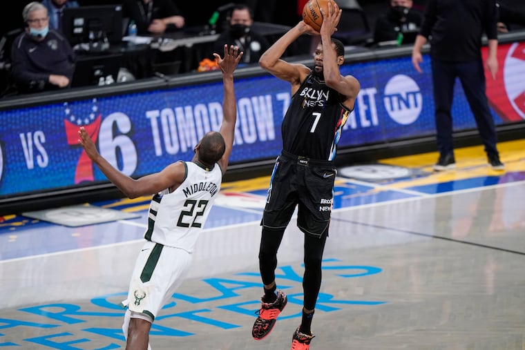 Nets forward Kevin Durant (right) shoots a three-pointer over Bucks forward Khris Middleton in an NBA second-round playoff game.