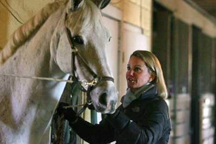 Janice Dugan greets "Cloudy," a boarder's horse, in the barn at Vince Dugan Stables in Unionville, Chester County. (Barbara L. Johnston / Staff Photographer)