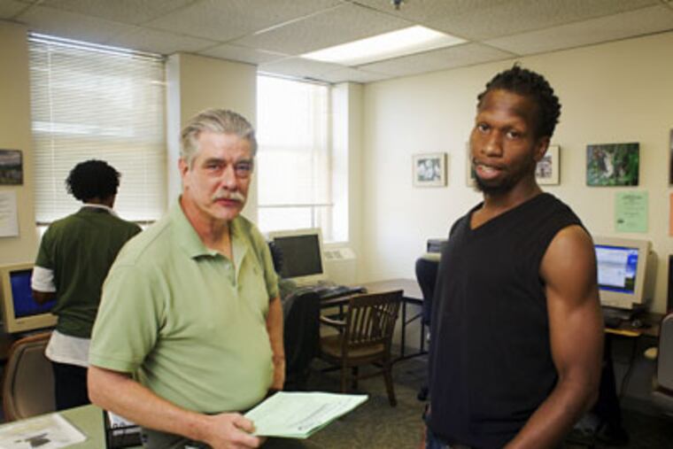 Kevin Copening, right, a truck driver, looks for work at the Philadelphia Unemployment Project office while talking with its director, John Dodds. The program is set to hold a run on Saturday to raise money for it's advocacy efforts aiding the unemployed find work. (Ed Hille / Staff Photographer)