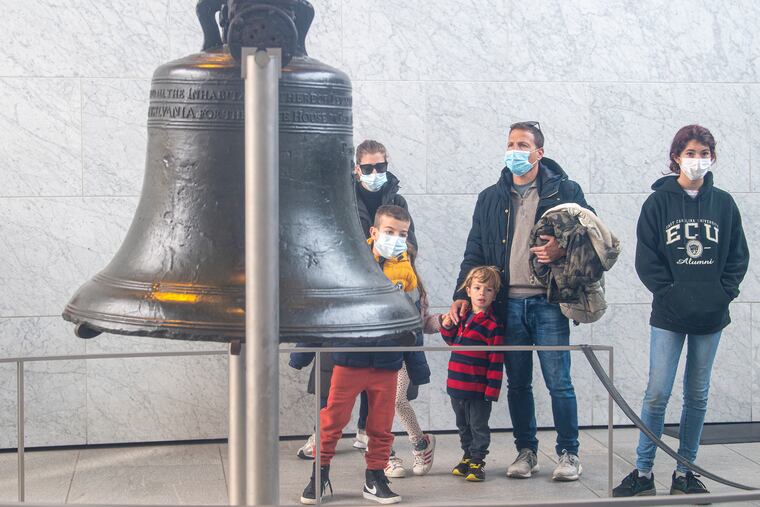 Visitors wearing masks look at the Liberty Bell last week at Independence Hall.
