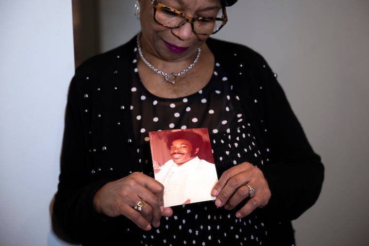 Mary Buffaloe with a photo of her brother Raymond Michael Caliman at her home in Philadelphia. The photo shows Raymond in 1980 on Mary’s wedding day.