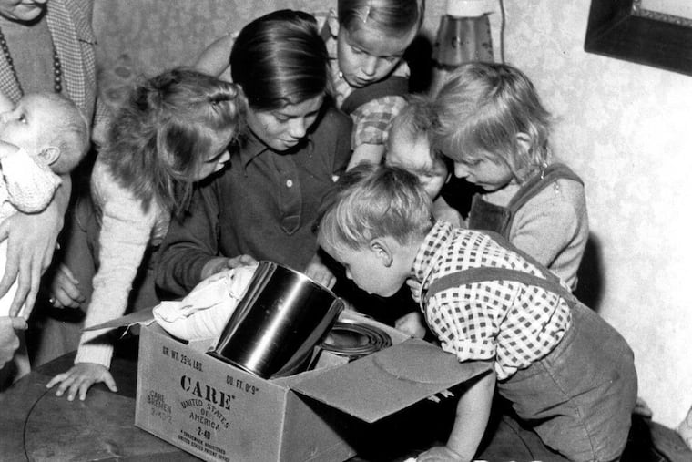 Children of a refugee family from East Germany crowd close to get a better view of the food in a CARE Package they received soon after they arrived in West Berlin in 1956.
