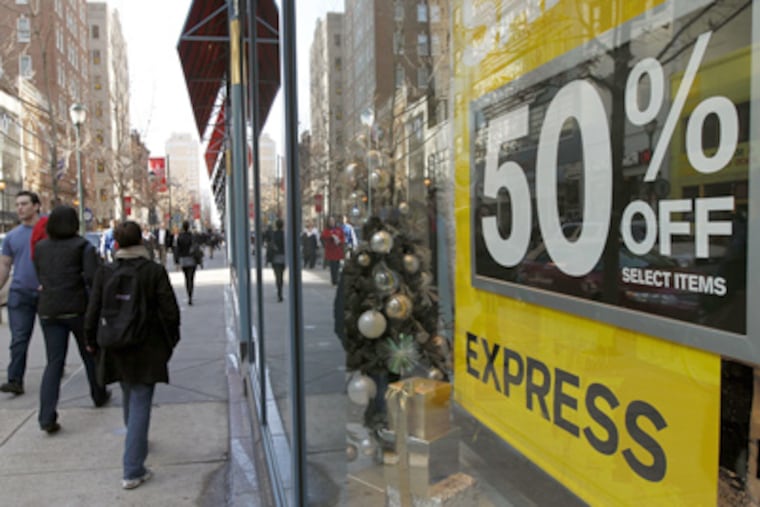 Pedestrians walk a shopping district as Express advertises a sale during the unseasonably warm weather in the few days before Christmas Thursday, Dec. 22, in Philadelphia. (AP Photo/Alex Brandon)