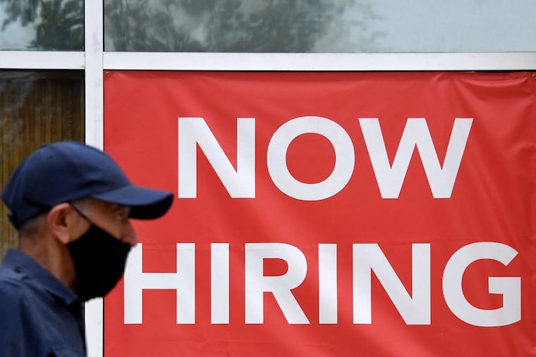 A man walks by a "Now Hiring" sign outside a store in Arlington, Va.