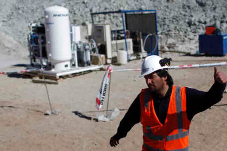 A worker gives a thumbs-up sign next to an oxygen plant used to send breathable air to the 33 miners trapped in the collapsed San Jose mine.