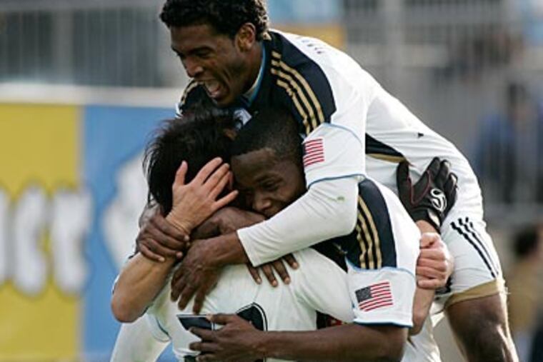 Sheanon Williams (top) and Danny Mwanga (center) celebrate a goal by Carlos Ruiz. (Tom Mihalek/AP Photo)