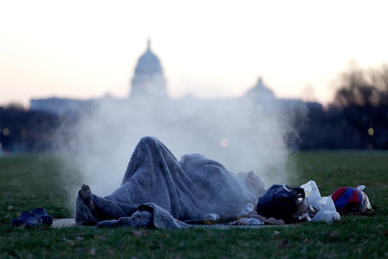 A homeless man rests on a steam vent along the National Mall in Washington, D.C., on Dec. 18, 2019.