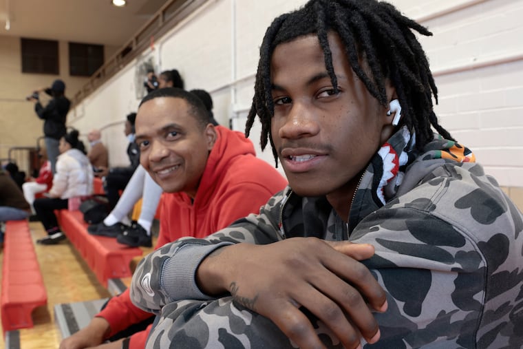 Dobbins Technical High School boys basketball coach Derrick Stanton (left) and basketball player Sam Thomas attend a girls basketball game at the school on Feb. 9.
