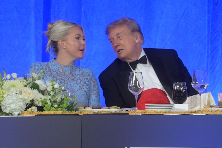 Donald Trump talks with White House press secretary Karoline Leavitt at the White House Correspondents' Association dinner Friday in Washington. The president's attacks on the media have helped erode public trust in journalism, writes the Editorial Board.