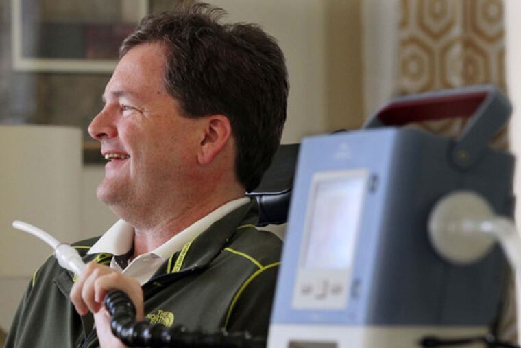 David Stuczynski, who has ALS, holds a tube from a machine that assists his breathing as he talks about recording his voice at the University of Akron on April 28, 2015 at his home in Brecksville, Ohio.