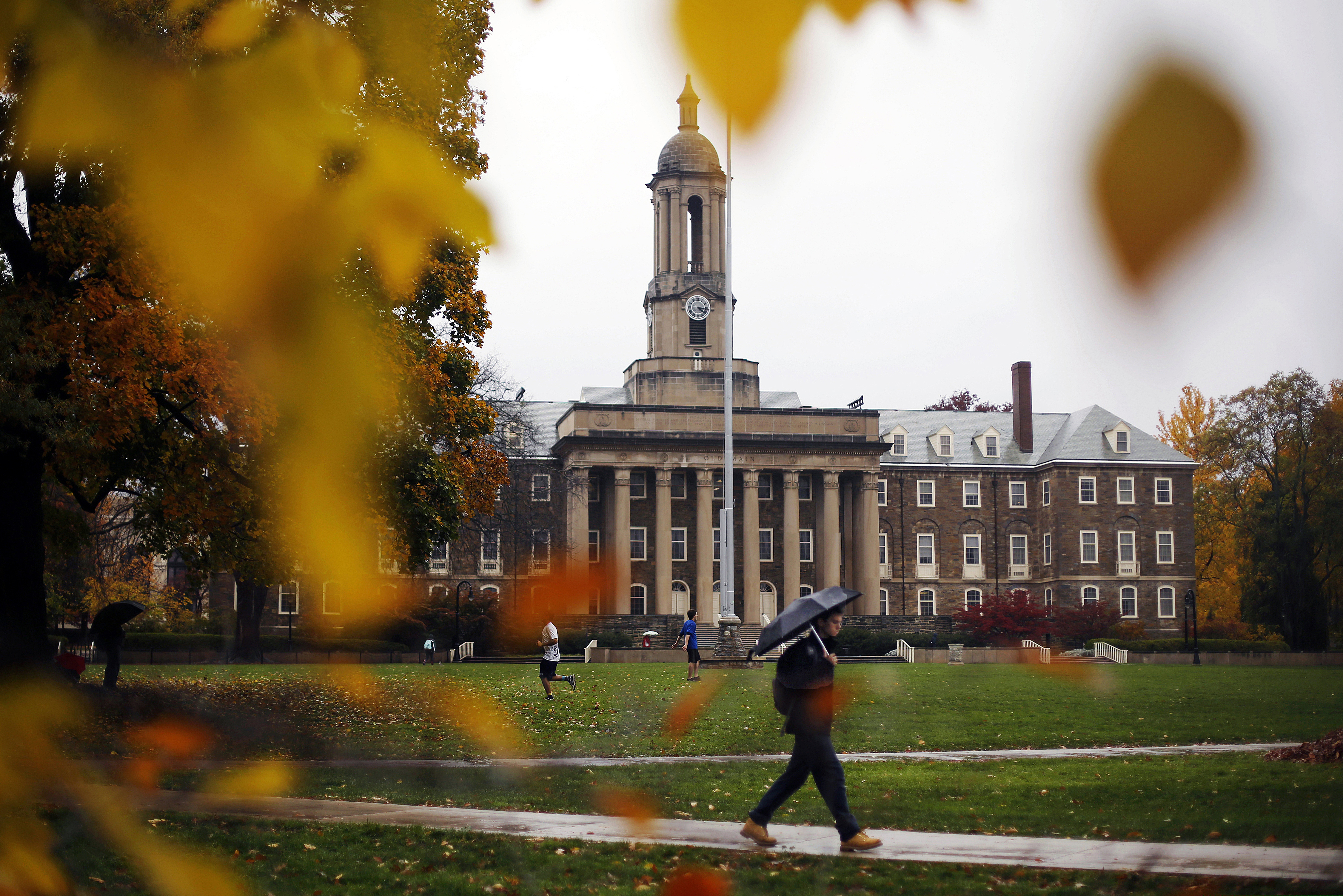 A Penn State student walks in the rain past Old Main on the Penn State main campus in State College in 2015. The school raised tuition this year after a three-year freeze.