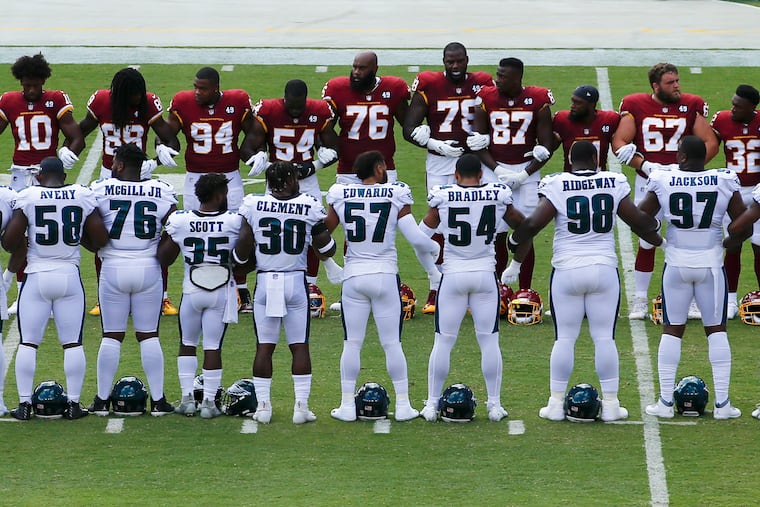 Members of the Eagles and the Washington Football Team gather in unity before the start of their game on Sunday.